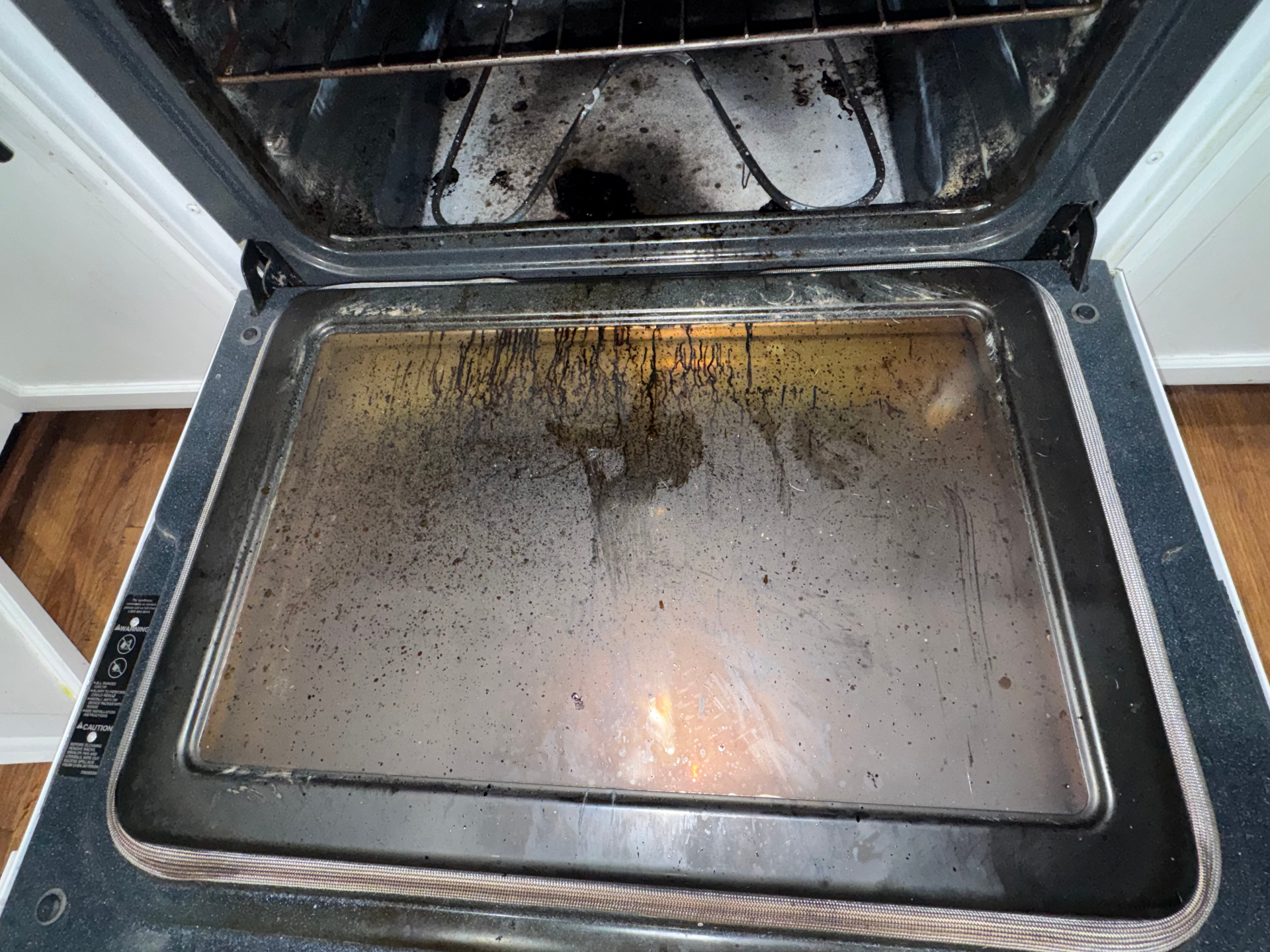 Oven door before cleaning, with heavy grease buildup